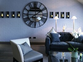 Una sala de estar moderna con un reloj de pared grande, un sofá, una silla y una mesa de centro.