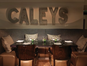 A dining area with a table set for four, two chairs on each side, and a large 'CALEYS' sign above. - Macdonald Windsor Hotel (Windsor)