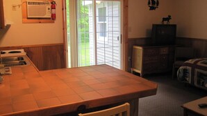 Une cuisine compacte avec un îlot central, un coin repas avec une table et des chaises, un téléviseur et une cheminée.