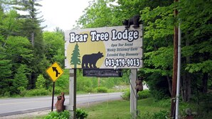 Une enseigne pour le Bear Tree Lodge, avec la silhouette d’un ours, un numéro de téléphone et un panneau indiquant qu’il faut tourner à gauche.