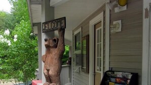 Une enseigne en bois avec le mot « BIENVENUE » fixée à la rambarde d’un porche, une boîte aux lettres et une bibliothèque remplie de livres.