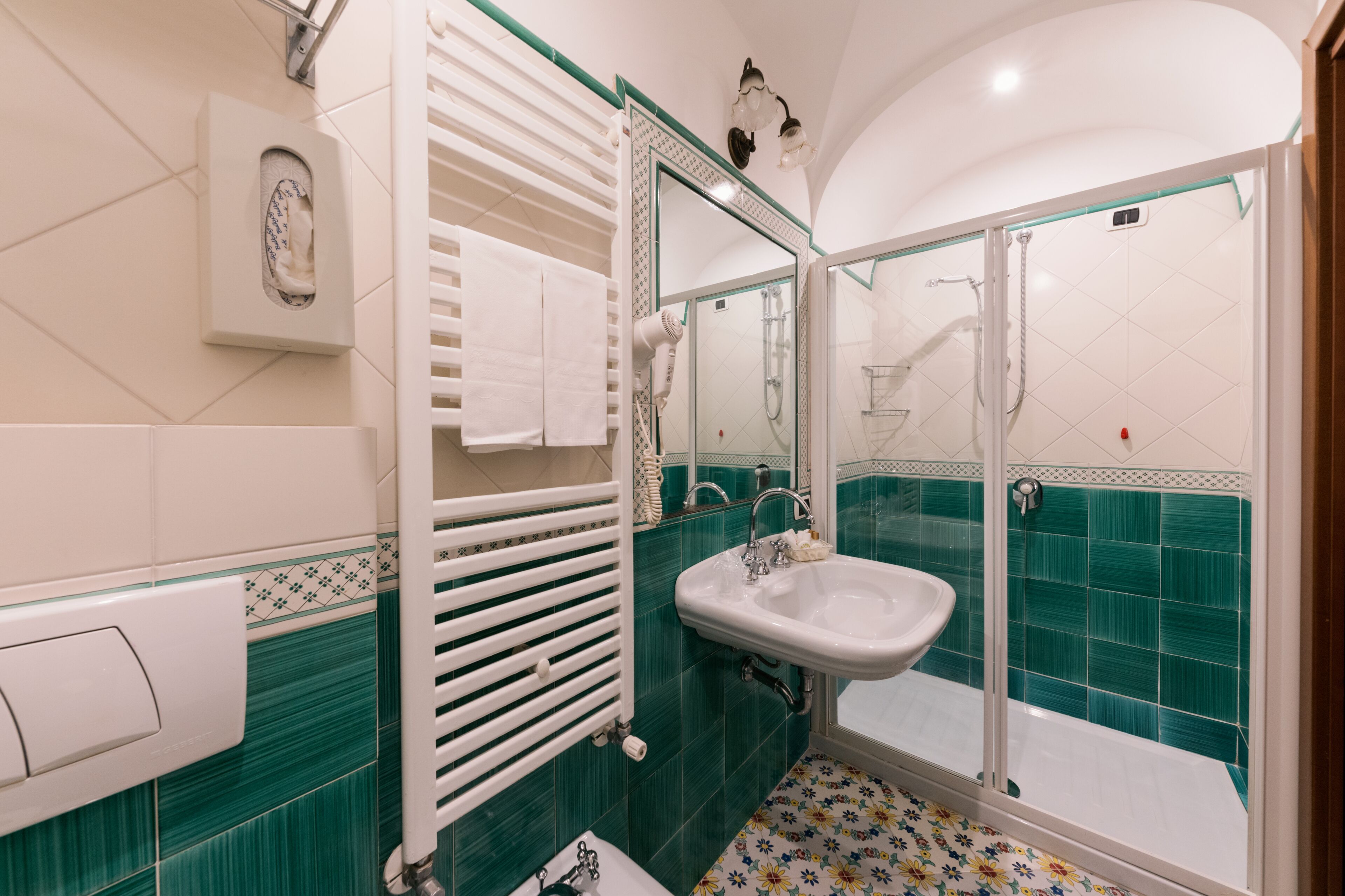A bathroom with a glass-enclosed shower, a white sink, and a towel rack.