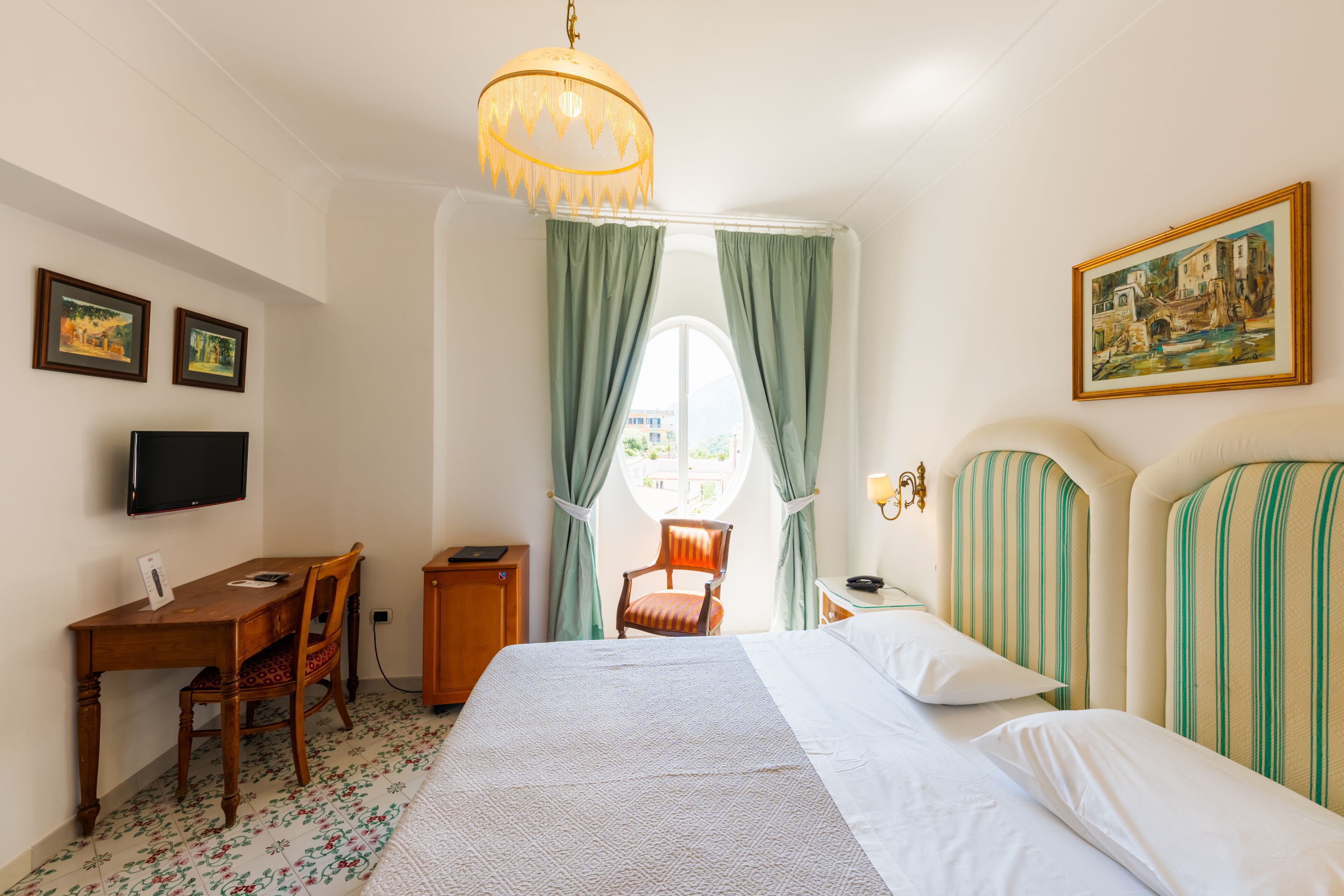 Une chambre d’hôtel avec un lit, un bureau, une chaise, une télévision et un tableau au mur.