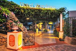 The entrance of Villa Maria Hotel Ristorante sul Mare with a lush garden and a welcoming sign.