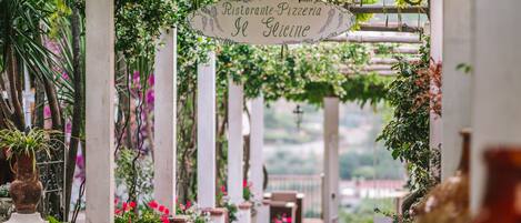 A covered outdoor area with a sign reading "Ristorante-Pizzeria Le Glicine."