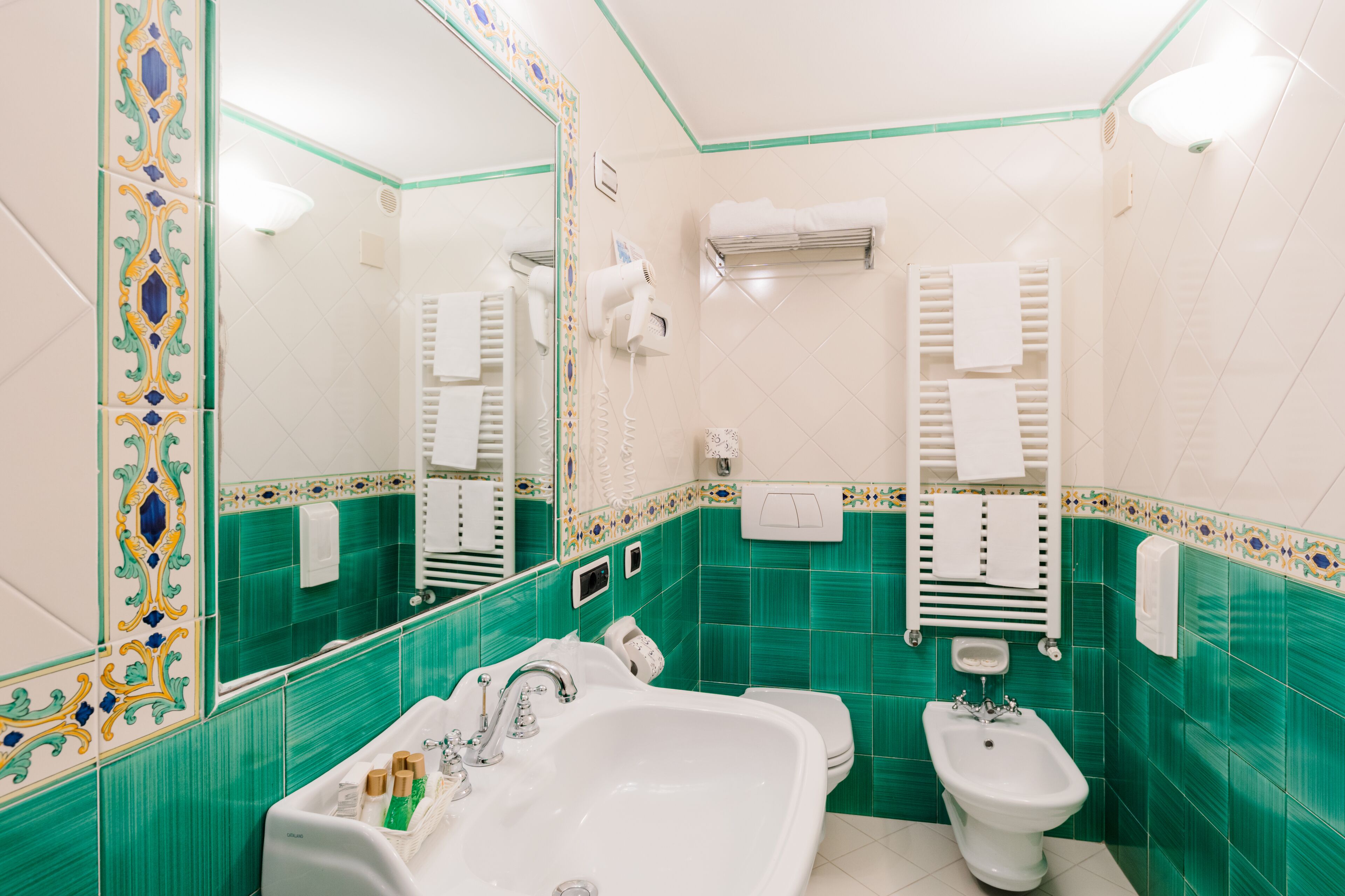 Un baño con lavamanos, bidé y espejo.
