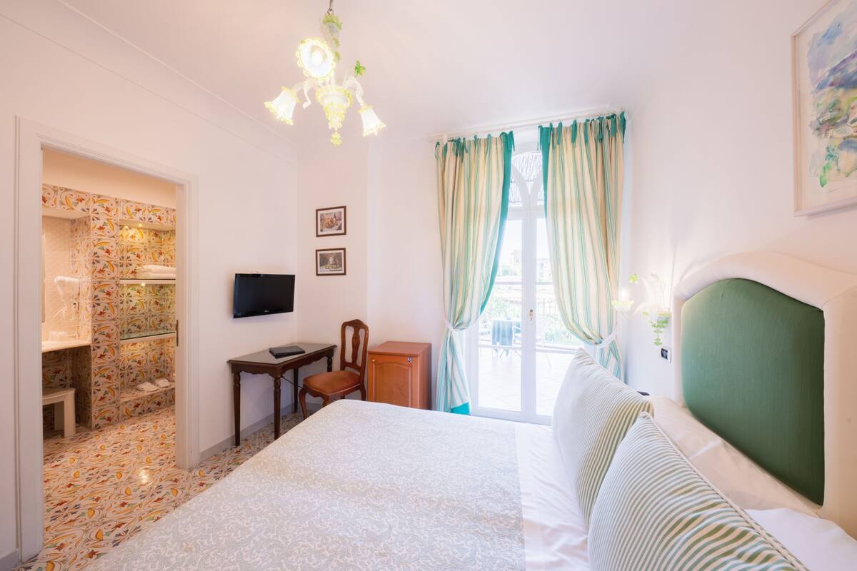 A bedroom with a bed, a desk, a chair, a TV, and a wardrobe.