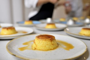 A dessert presentation with caramel-topped flan on white plates.
