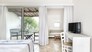 A hotel room with a bed, a desk with a television, a chair, a small table, and a balcony with a bench.