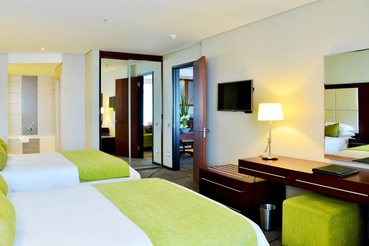Une chambre d’hôtel avec deux lits, un bureau, une chaise, une télévision et une salle de bain.