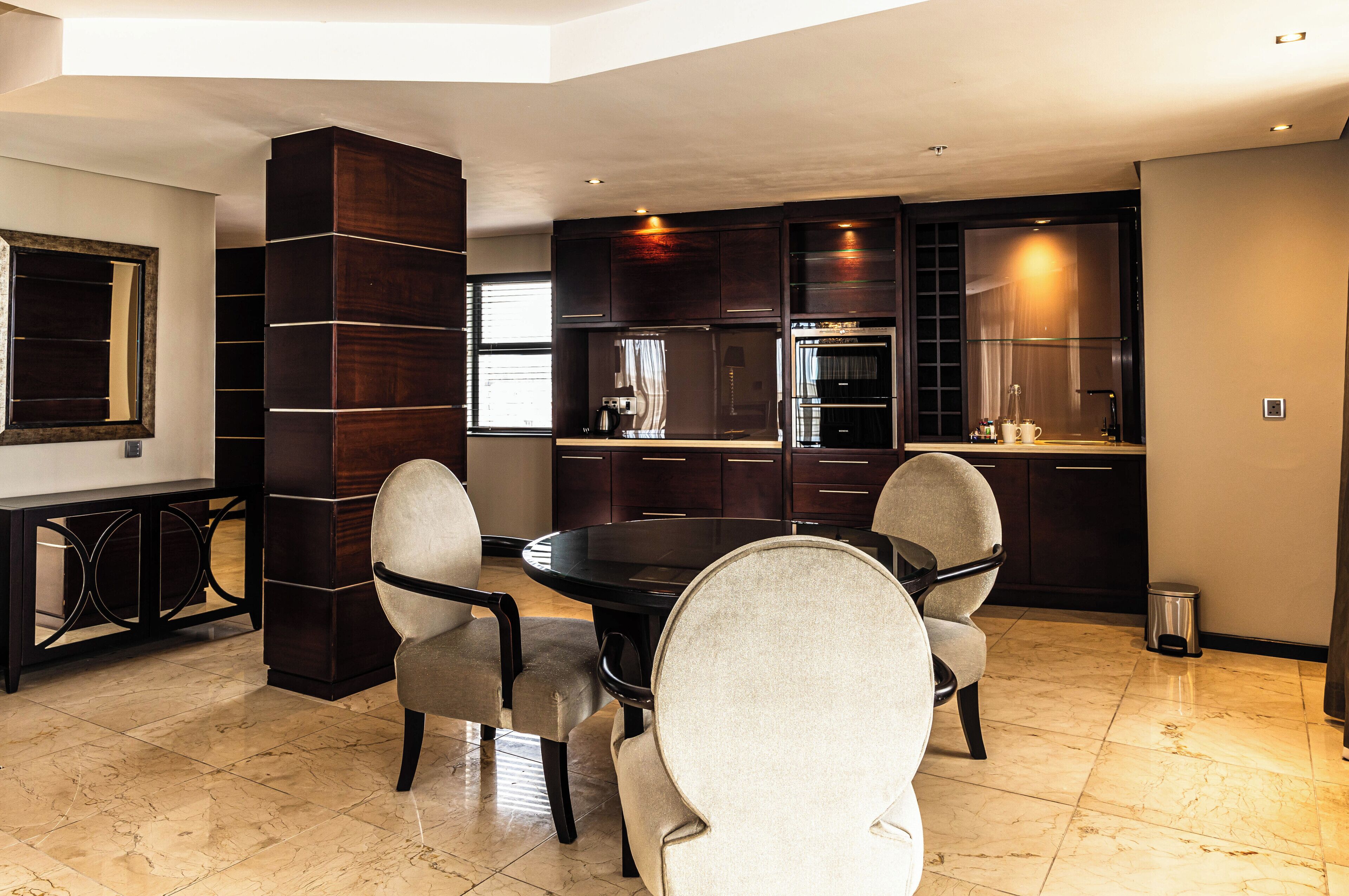 A modern kitchen with dark wood cabinets, a round dining table, and four chairs.