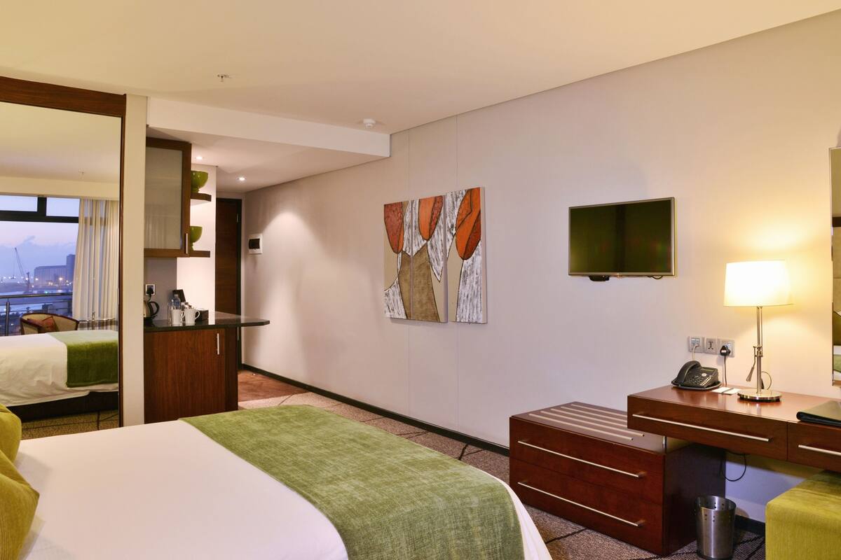 Une chambre d’hôtel avec un lit, un bureau, une chaise, une télévision et des œuvres d’art accrochées au mur.