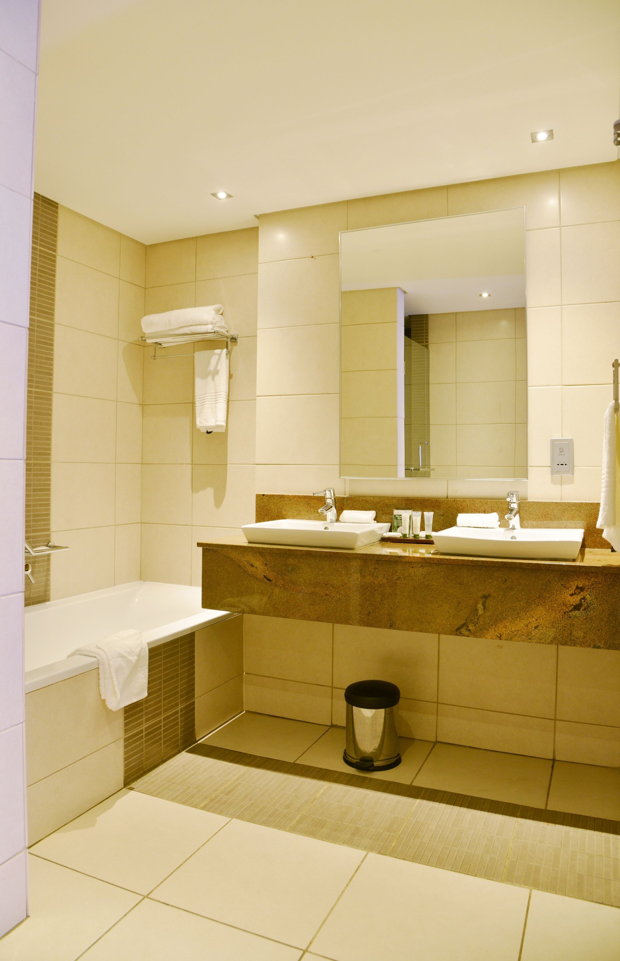 A modern bathroom with a double sink, a large mirror, and a bathtub.