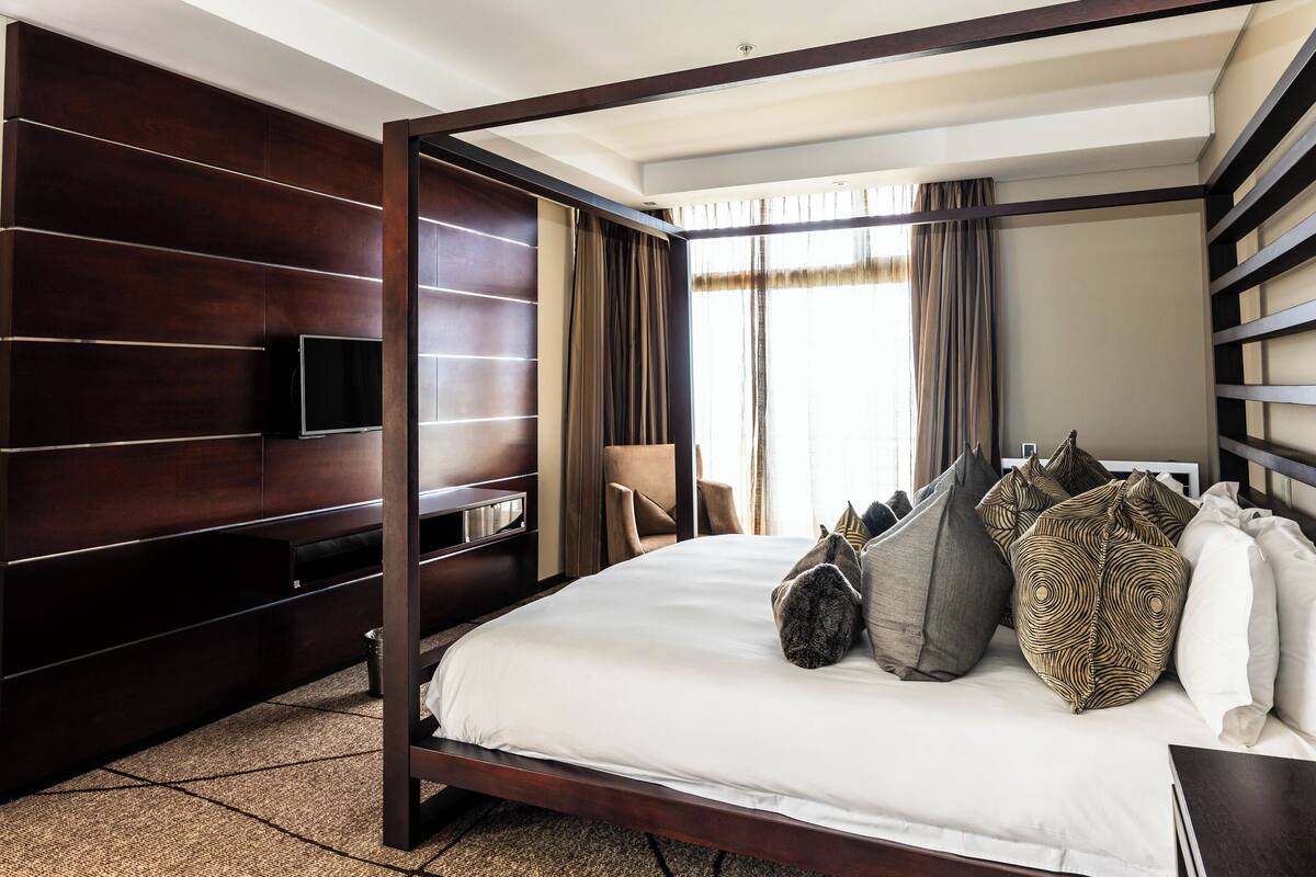 Une chambre d’hôtel moderne dotée d’un grand lit, d’un téléviseur fixé au mur et offrant une vue sur l’extérieur par la fenêtre.