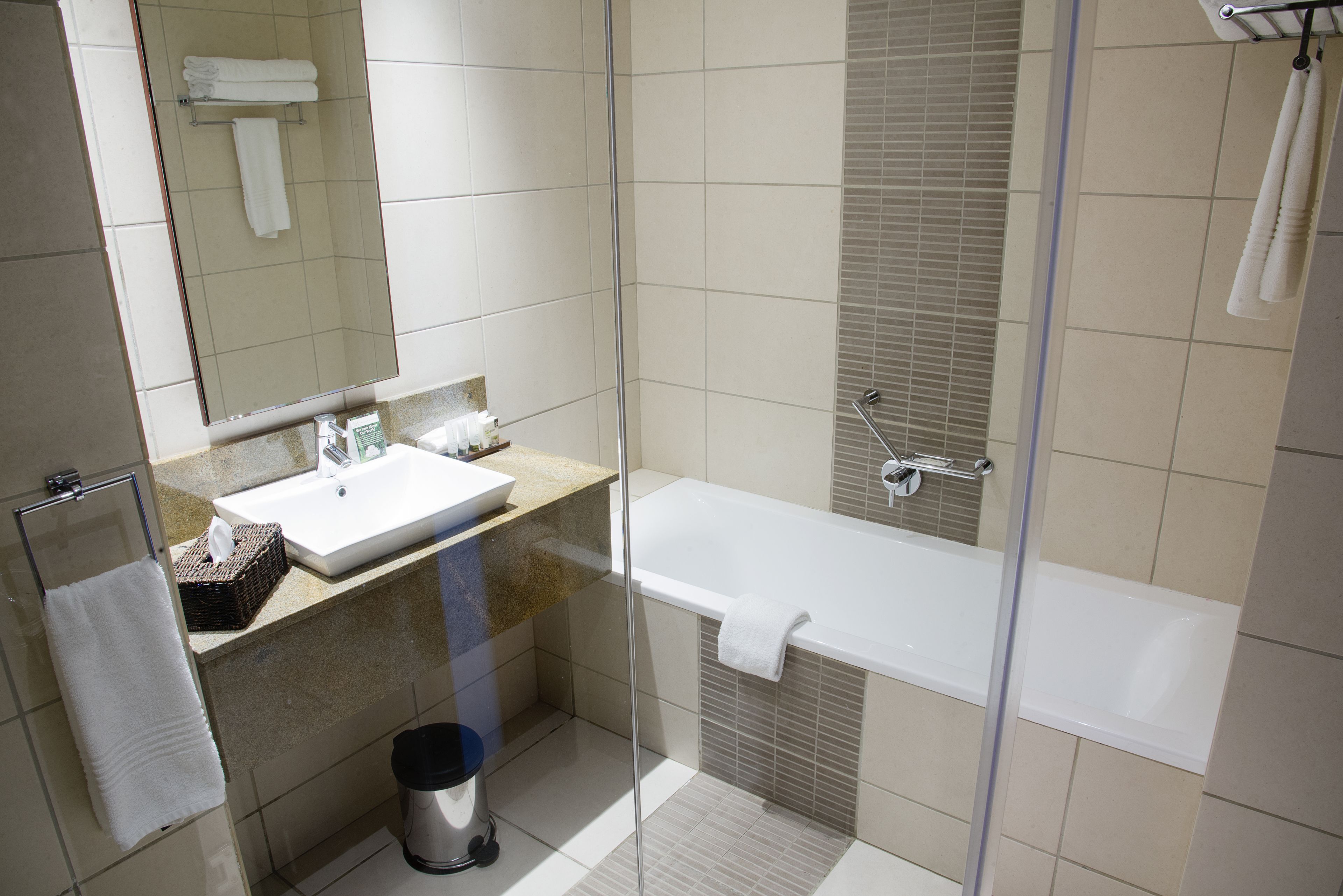 Een moderne badkamer met een douchekabinet van glas, een wit wastafelmeubel en een bad.