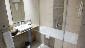 Een moderne badkamer met een douchekabinet van glas, een wit wastafelmeubel en een bad.