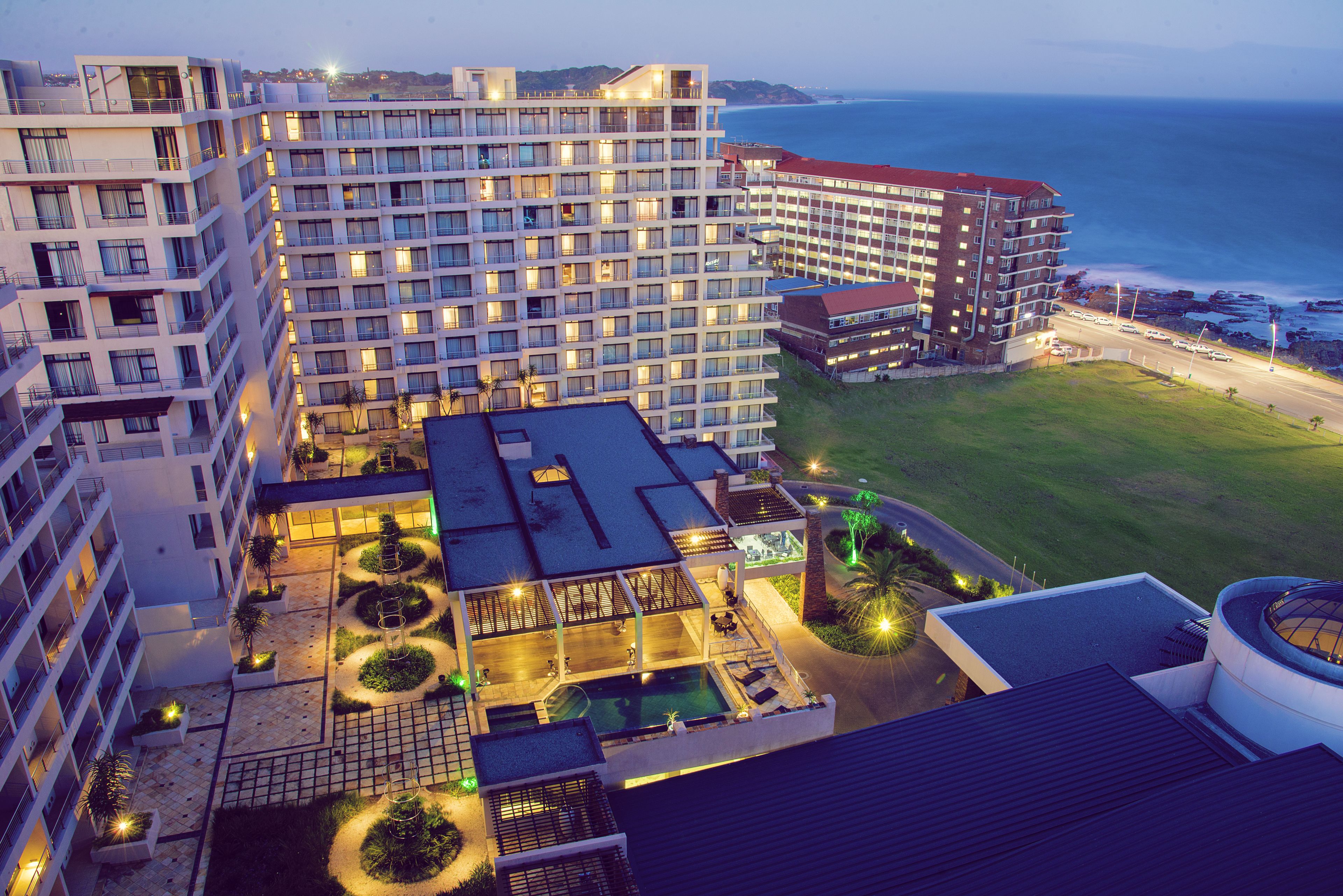 A hotel with multiple floors, outdoor swimming pools, and a view of the ocean.