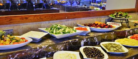 Un buffet proposant une variété de plats, notamment des salades, des fruits et des fromages.