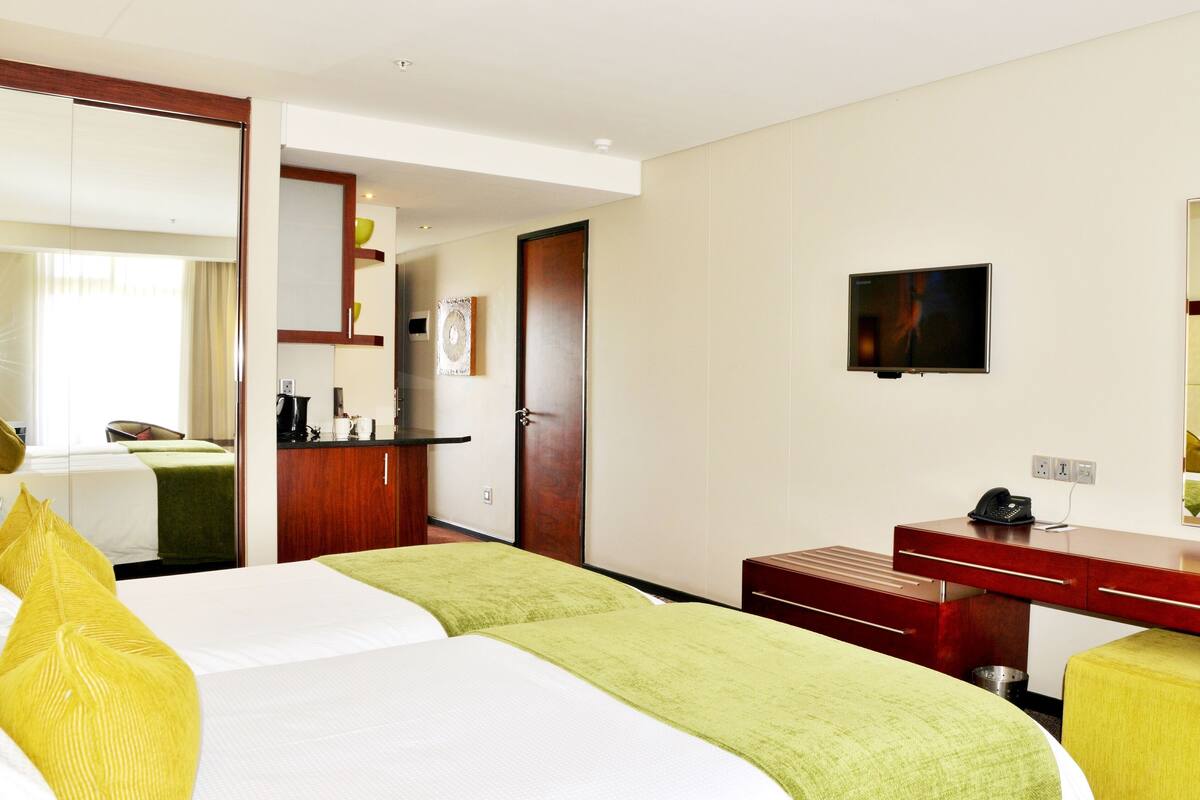 Une chambre d’hôtel équipée d’un lit, d’un bureau, d’une chaise, d’une télévision et d’un miroir.
