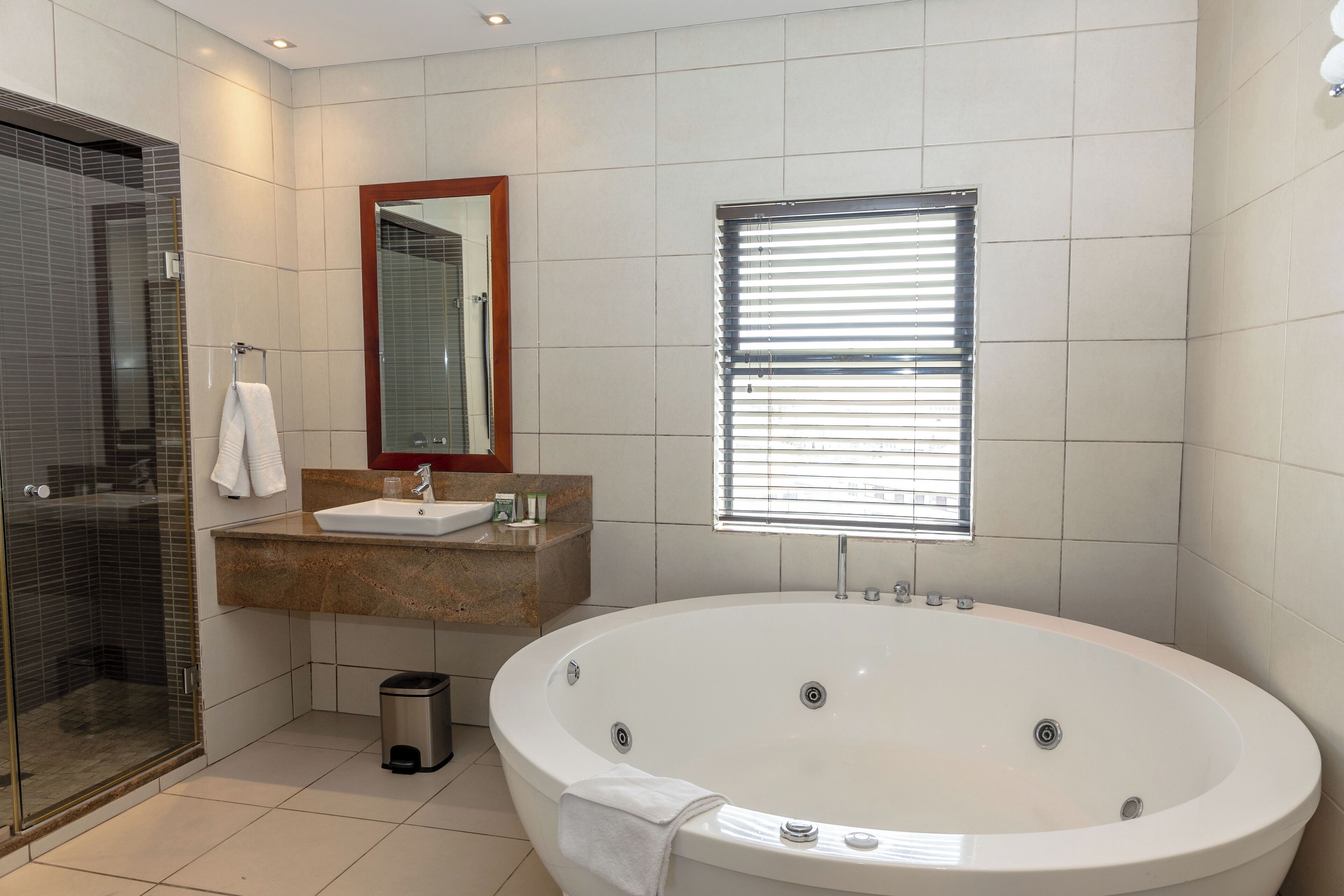A modern bathroom with a glass-enclosed shower, a freestanding bathtub, a vanity with a sink, and a mirror above the sink.
