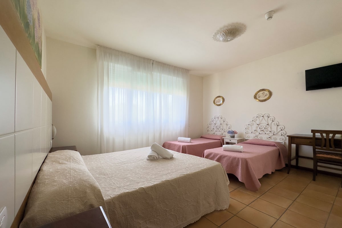 A hotel room with two beds, a desk, and a television on the wall.