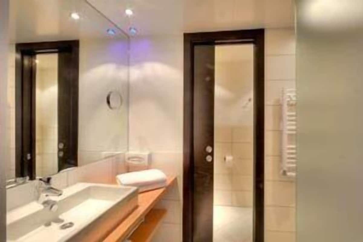 A modern bathroom with a large mirror, a sink, and a shower area.
