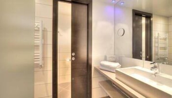 Un baño moderno con un espejo grande, un lavamanos y un perchero para toallas.