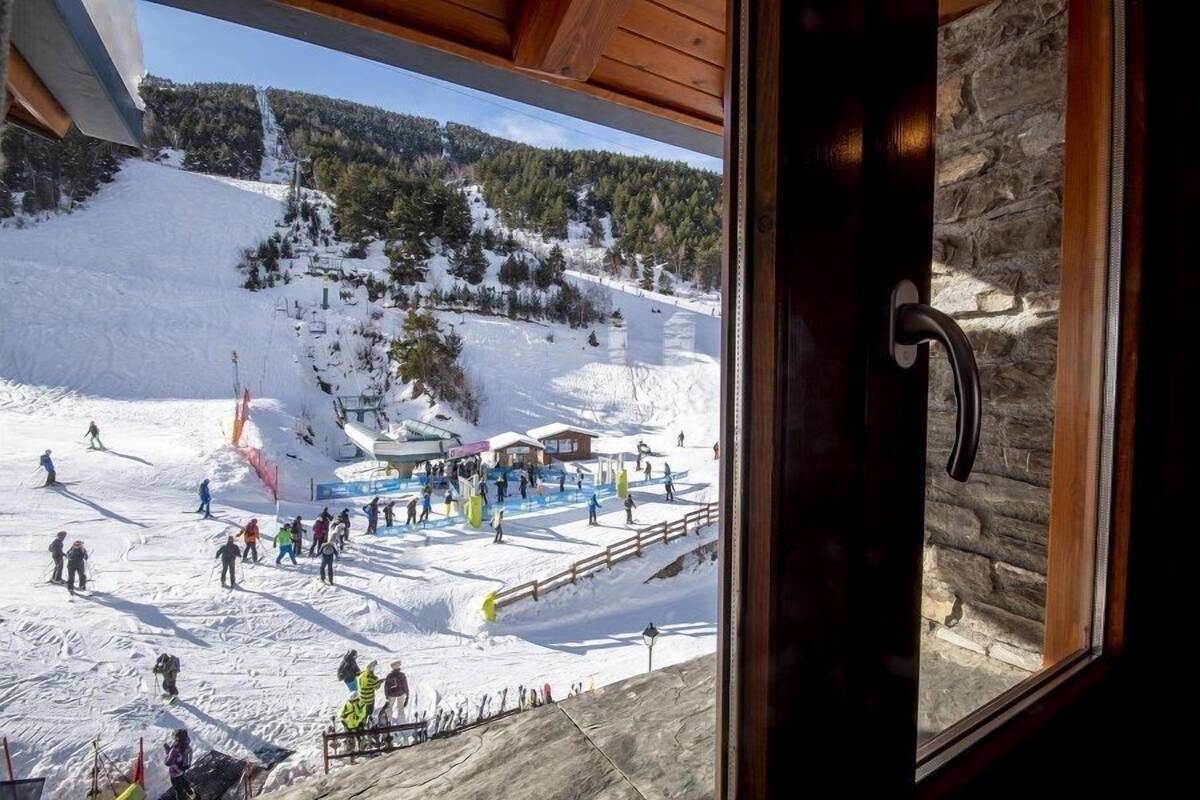 A ski resort with a wooden building, a ski lift, and a snowy landscape.