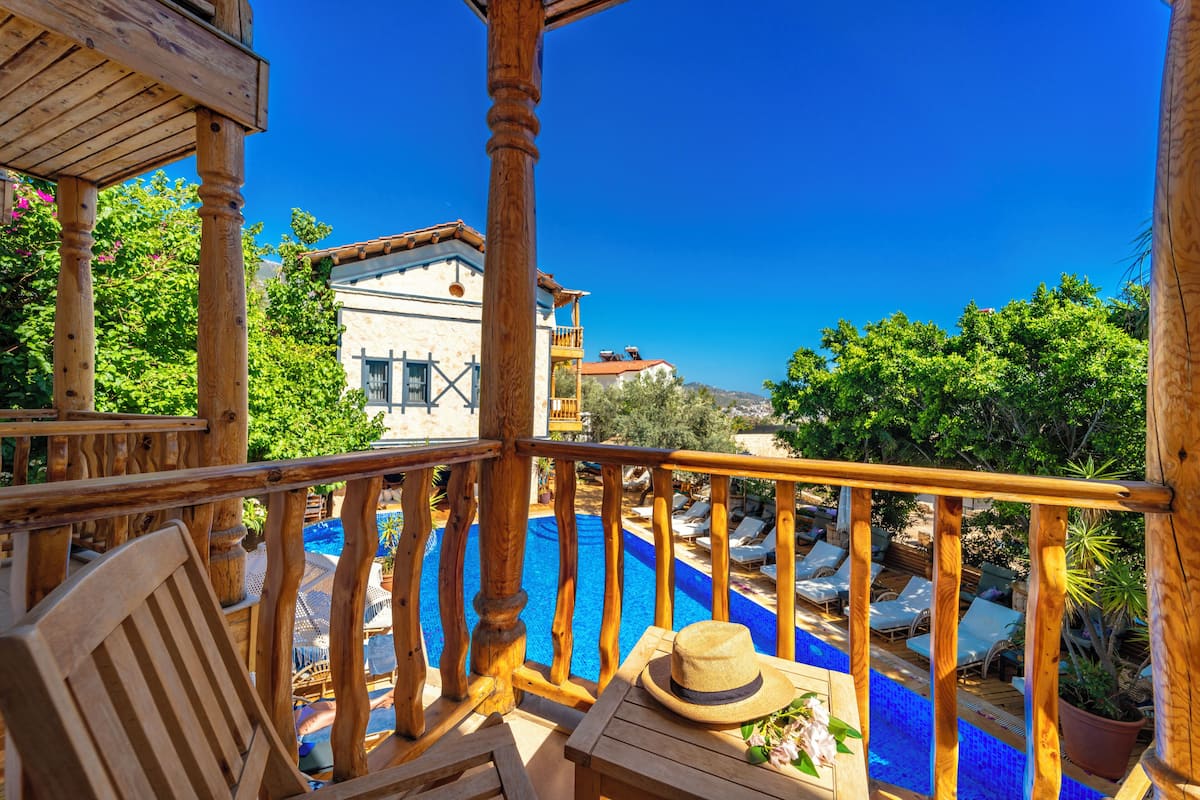 A wooden deck with a pool, lounge chairs, and a hat on a table.