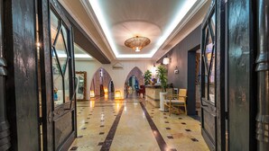 A hotel lobby with a marble floor, arched doorways, a reception desk, and a ceiling light fixture. - Elixir Boutique Hotel (Kalkan)