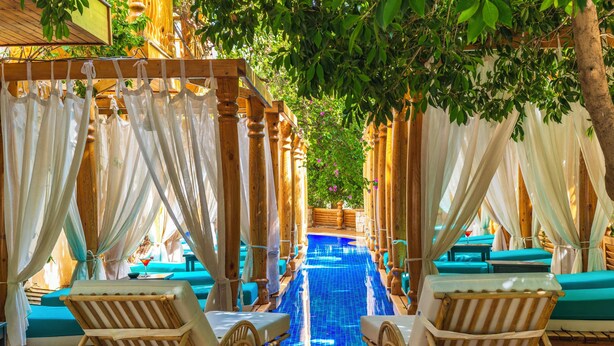 A pool area with wooden loungers and a blue-tiled pool, surrounded by white drapes and wooden pillars. - Elixir Boutique Hotel (Kalkan)