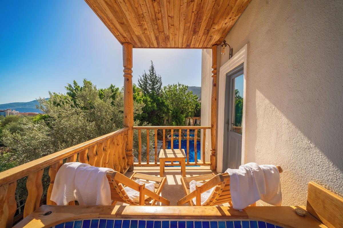 A wooden deck with a pool, wooden chairs, and a table.