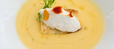 A white plate with a piece of white food topped with sauce and garnishes.