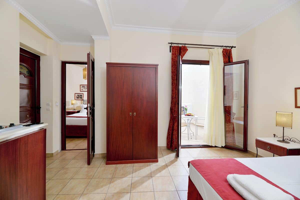 Habitación de hotel con cama, armario, escritorio y baño visible a través de una puerta abierta.