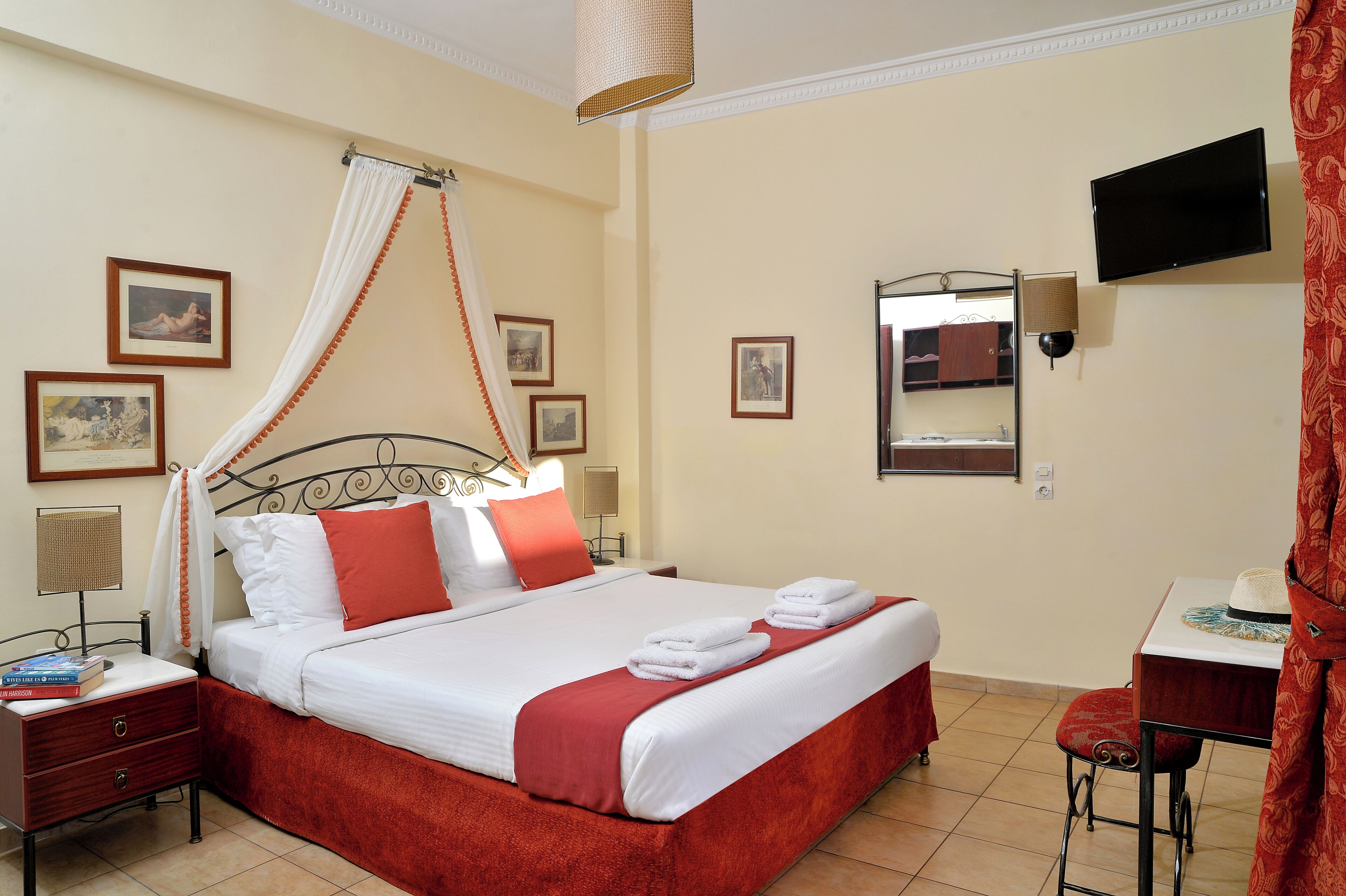 A neatly arranged hotel room with a bed, bedside tables, a TV, and a small table with a chair.