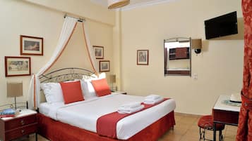 A neatly arranged hotel room with a bed, bedside tables, a TV, and a small table with a chair.