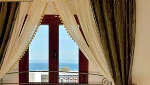 A bed with a view of the sea, curtains, a bedside table, and a lamp. - Hotel Agistri (Agistri)