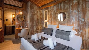 Um quarto estilo cabana de madeira, com uma cama grande, duas mesas de cabeceira, uma cadeira e um espelho na parede.