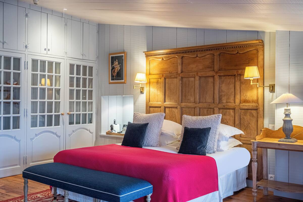 Une chambre à coucher avec un grand lit, une tête de lit en bois, une armoire blanche et des lampes de chevet.