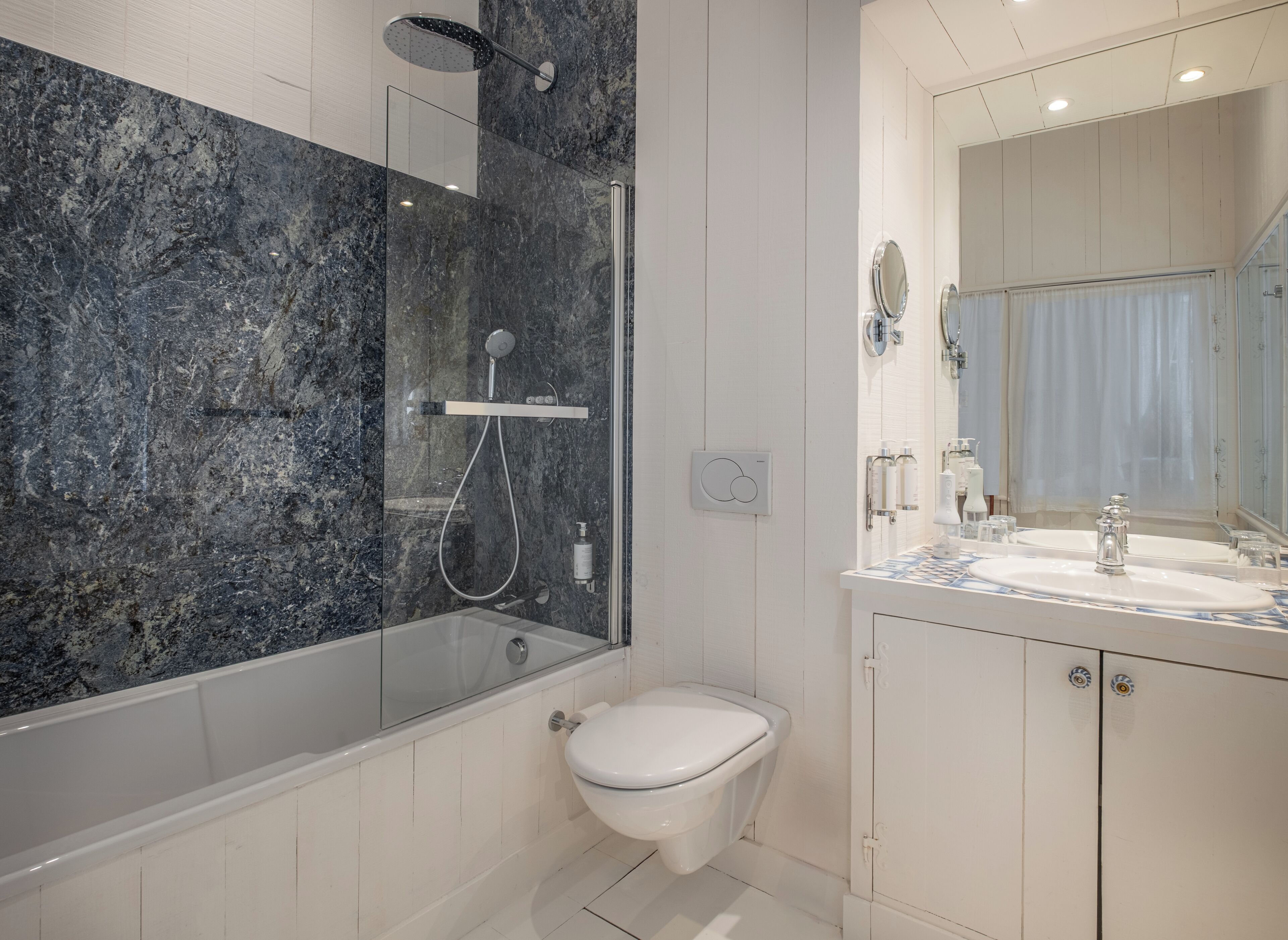 A modern bathroom with a glass-enclosed shower, a toilet, and a vanity with a mirror.