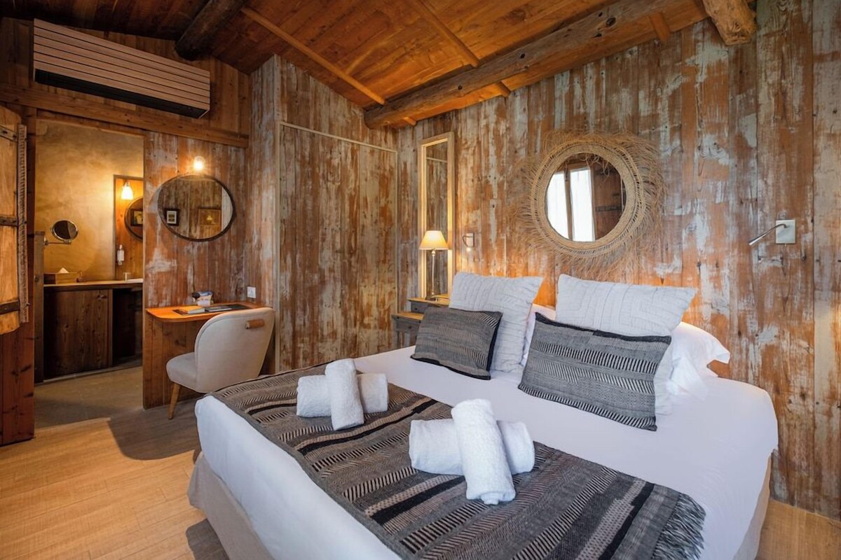 Un dormitorio tipo cabaña de madera con una cama grande, un escritorio y un espejo.