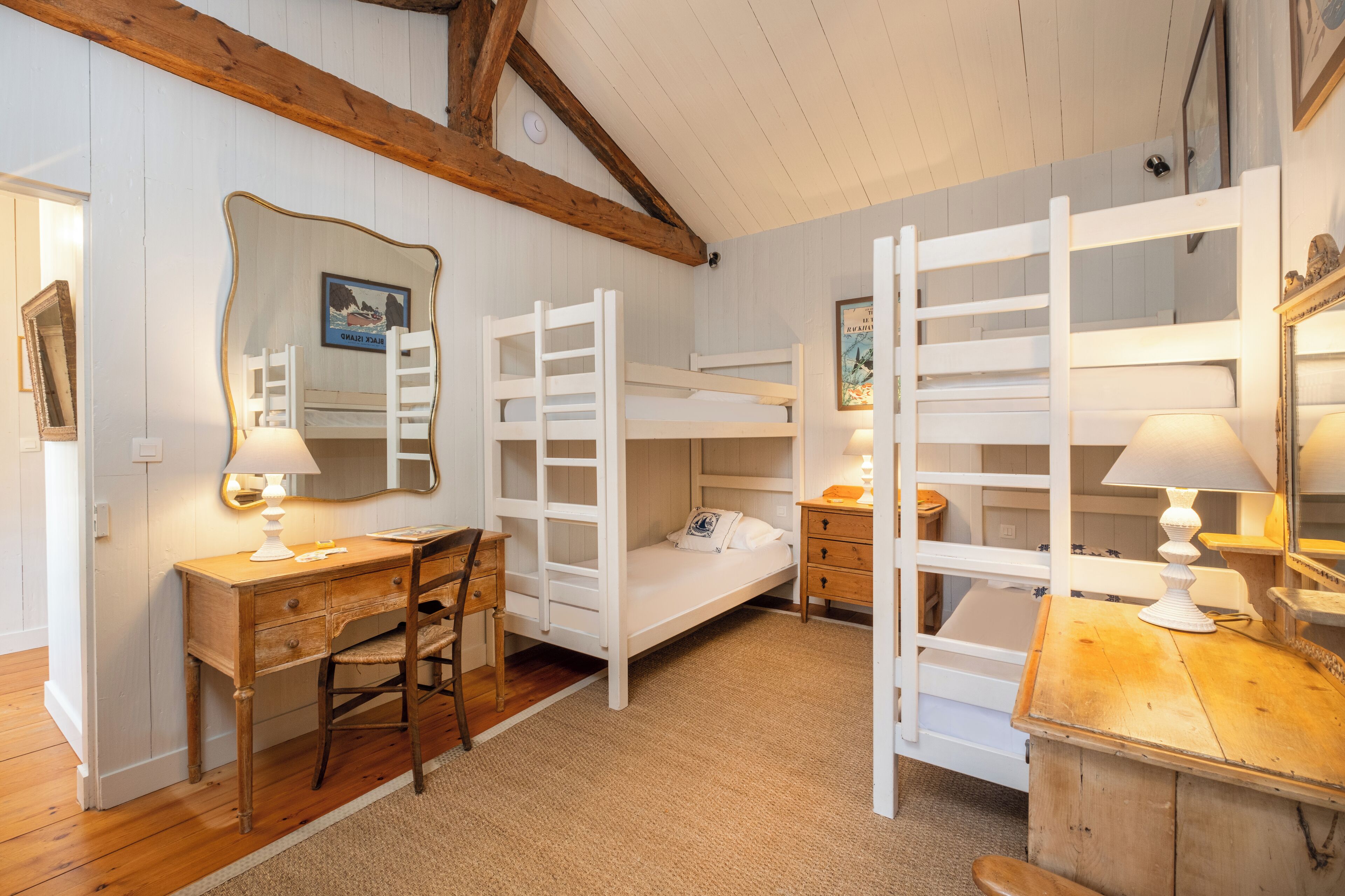 A room with bunk beds, a desk, a chair, and a dresser.