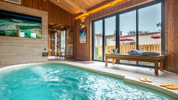 Área da piscina com deck de madeira, um banco e vista para o exterior.