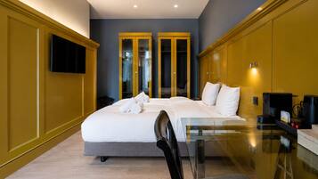 A hotel room with a bed, a glass table, a chair, a TV, and a coffee machine.