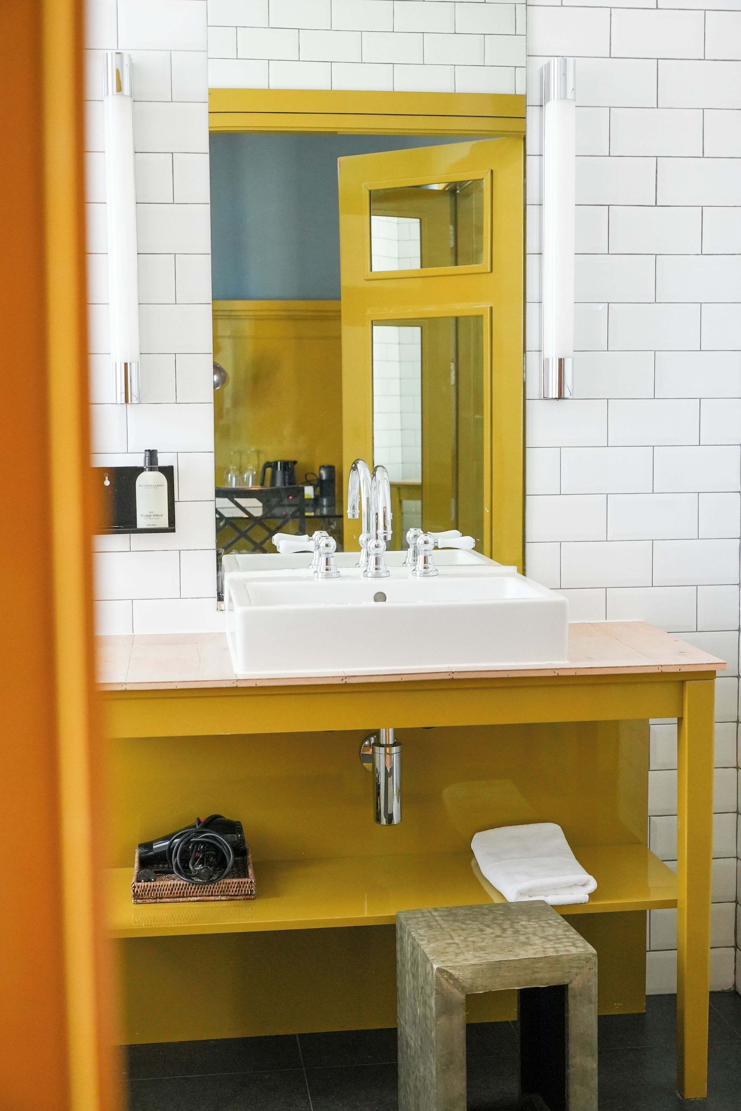 Une salle de bain avec un lavabo blanc, un miroir et un meuble-lavabo jaune.
