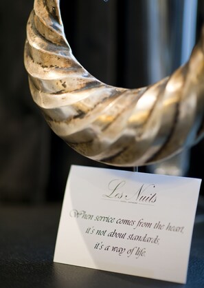 A curved, metallic object with a textured surface, possibly a decorative item, and a sign with text below it.