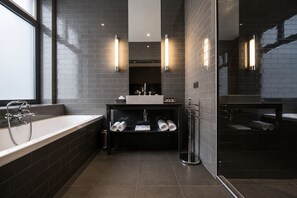 A modern bathroom with a bathtub, a vanity with a mirror, and towel racks. - Les Nuits Hotel (Antwerp)