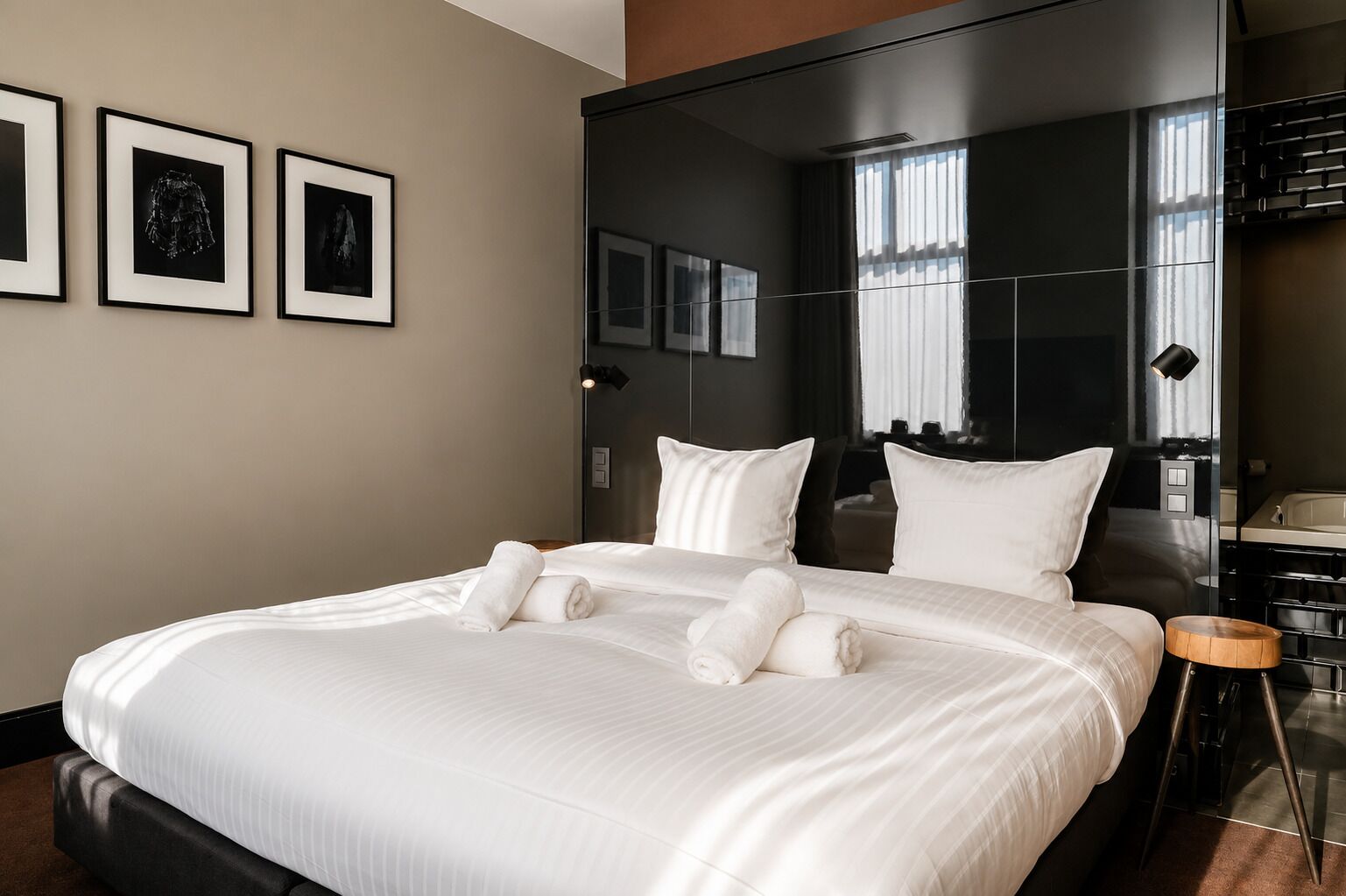 Une chambre d’hôtel avec un grand lit, un miroir et des tableaux encadrés accrochés au mur.