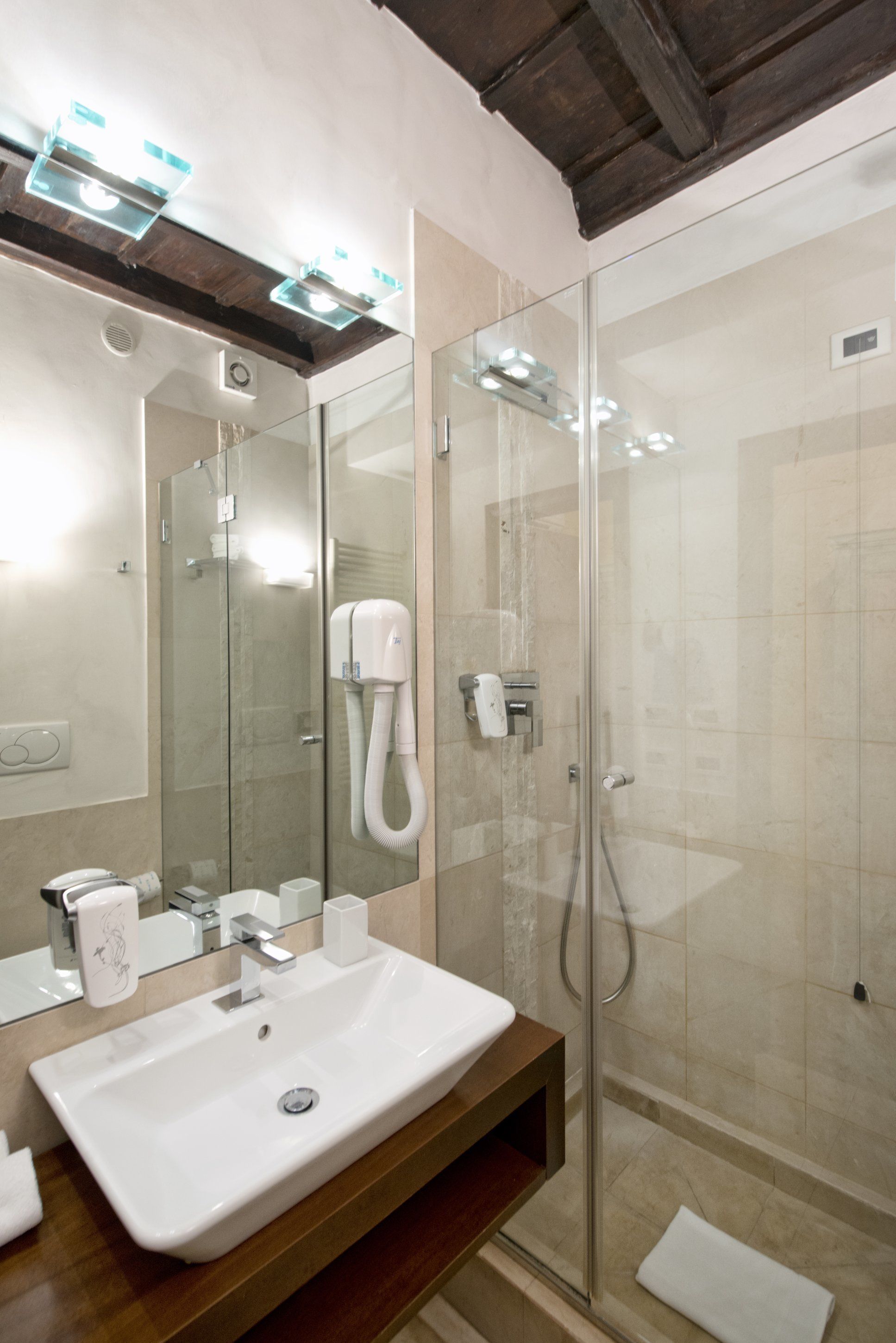 Une salle de bain moderne avec une douche à parois de verre, un lavabo blanc et un grand miroir.