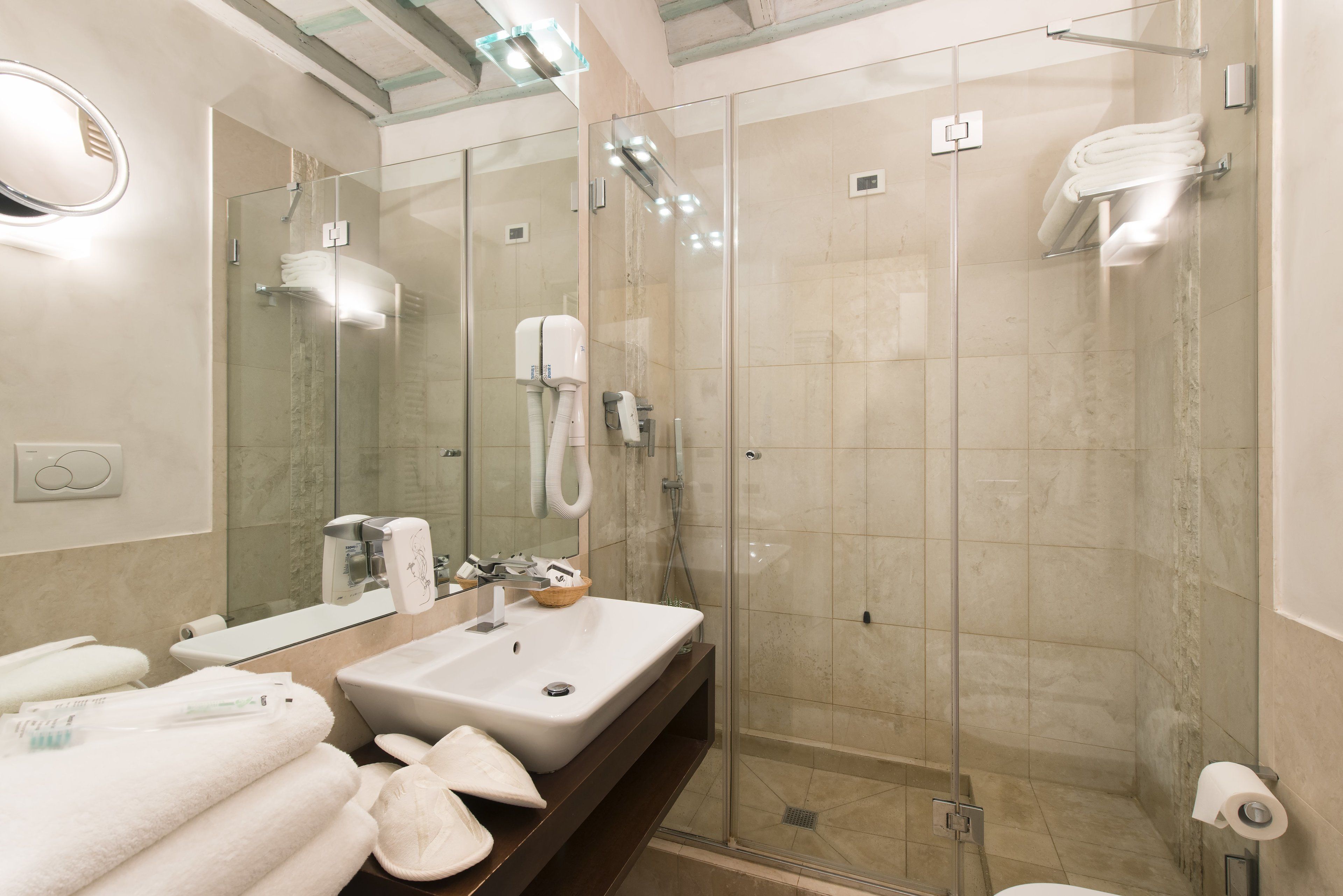 Ein modernes Badezimmer mit einer Glaskabine zur Dusche, einem großen Spiegel und einem Waschtisch mit Spüle und Handtuchhalter.
